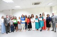 ParaTodosVerem: Fotografia em ambiente fechado, nela, estão homesn e mulhures, todos de pé e sorrindo para a foto.