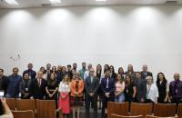 Fotografia em ambiente fechado que reúne dezenas de pessoas entre homens e mulheres. 
