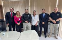 Fotografia colorida em ambiente fechado, na foto estão presentes 5 servidores ao lado do agente de policia judicial, Mateus