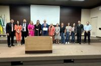 #ParaTodosVerem: Fotografia colorida em ambiente fechado mostrando o certificado do selo de linguagem simples, na foto está pres