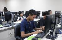 Descrição de imagem: Fotografia contendo algumas crianças e adolescentes mexendo em um computador. 