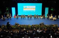 Foto colorida tirada durante a premiação. Os indicados estão no palco sentados durante uma roda de conversa. 