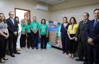 Foto colorida do momento da entrega de alimentos. Próximo às doações, sete representantes do TRT8, incluindo o presidente, e qua