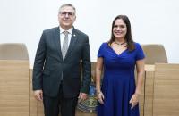 Fotografia em ambiente fechado que reúne lado a lado, um homem branco de terno escuro e uma mulher branca de vestido azul