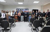 Fotografia em ambiente fechado que reúne dezenas de pessoas entre homens e mulheres. 