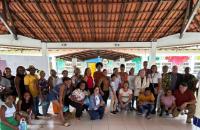 Foto colorida de um grande grupo de moradores de curiaú junto a magistrados do TRT8 em visita a uma escola local.