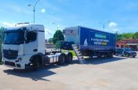 Foto colorida mostra um caminhão com uma carreta azul da Justiça do Trabalho, levando atendimento móvel.
