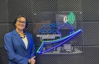 Foto colorida da juíza Núbia Guedes posando ao lado da logo da rádio do TJ Amapá.