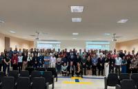 Fotografia em ambiente fechado que reúne dezenas de pessoas em pé, lado a lado, entre homens e mulheres