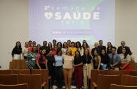 Fotografia em ambiente fechado que reúne dezenas de pessoas entre homens e mulheres, lado a lado, sorrindo. 