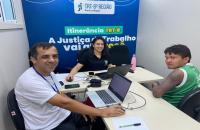 Fotografia em ambiente fechado que reúne três pessoas em atendimento na carreta do TRT-8, entre eles, um indígena, uma mulher e 