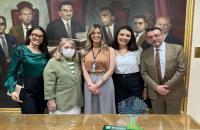 Fotografia em ambiente fechado que reúne quatro mulheres e um homem, todos lado a lado, sorrindo. 