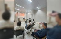 Descrição de imagem: Fotografia em ambiente fechado que reúne diversas pessoas em uma audiência de conciliação no Fórum Trabalhi