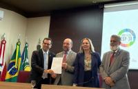 Foto em ambiente fechado mostrando os ministros do TST e o representante da OIT na cerimônia de assinatura do Plano de Trabalho.