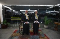 Fotografia em ambiente fechado de dois homens, lado a lado, vestido com uma toga