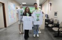 Fotografia de um mulher e um homem, em mãos seguram a camisa da Campanha do Círio 2025