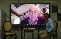 #ParaTodosVerem: Foto em espaço fechado, com o sociólogo Christian Laval em um telão e o professor Jean François Yves Deluchey a