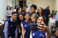 9 pessoas em pé segurando um telefone celular fazendo uma selfie com os coletes azuis.