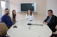 Na foto a presidente o representante da abine o juiz sentados em uma mesa na sala.