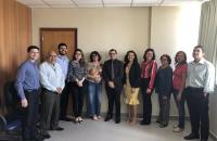 servidores todos em pé ao fundo claro olhando para foto.