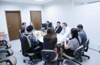 Foto mostra reunião dos membros da comissão sentados em torno de uma mesa redonda.