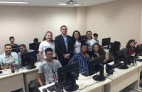 Foto mostra jovens no laboratório de computação para início do curso PJE  com membros da comissão.