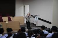 Foto da Desembargadora Sulamir Monassa no auditório falando para estudantes