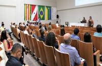 Na foto: O auditório cheio de pessoas com a palestrante ao fundo.