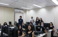 Foto: jovens sentados em frente aos computadores na sala de informática da Comissão.