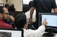 Na foto: dois servidores da SETIN participando da capacitação, conversando sentados de frente para computadores.