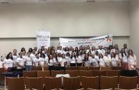 Foto: Parceiros vestidos com a camiseta da campanha carregam faixas e banner sobre a II Marcha no auditório da Ejud.
