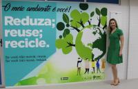 Foto: Juíza presidente da comissão de gestão ambiental ao lado da parede onde está a plotagem com as ações do TRT8 sustentável.