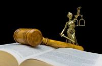 Imagem de malhete em cima de um livro, com o simbolo da divindade grega Dice segurando uma balança da justiça atrás.
