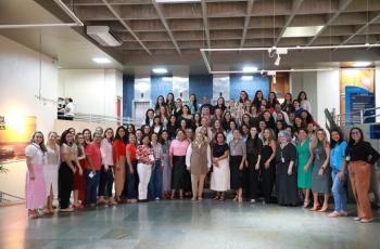 Fotografia em ambiente externo que reúne dezenas de mulheres lado a lado, em pé e sorrindo