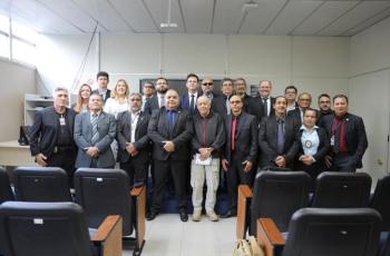 #ParaTodosVerem: Fotografia colorida em ambiente fechado, na foto está reunido diversas pessoas em pé, sorrindo.