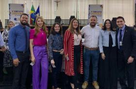 Fotografia em ambiente fechado de sete pessoas lado a lado, sendo quatro mulheres e três homens