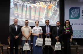  Fotografia em ambiente fechado. Em primeiro plano, os seis participantes do painel