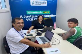 Fotografia em ambiente fechado que reúne três pessoas em atendimento na carreta do TRT-8, entre eles, um indígena, uma mulher e 