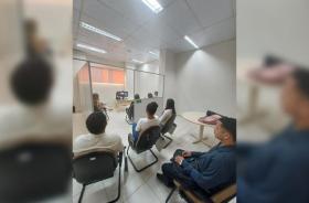 Descrição de imagem: Fotografia em ambiente fechado que reúne diversas pessoas em uma audiência de conciliação no Fórum Trabalhi