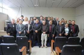 #ParaTodosVerem: Fotografia colorida em ambiente fechado, na foto está reunido diversas pessoas em pé, sorrindo.